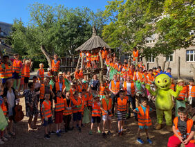 Kinder mit orangenen Westen und der hessische Umweltminister machen ein Gruppenfoto.