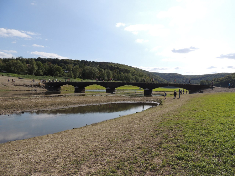 Eine Bogenbrücke führt über einen kleinen Fluss.