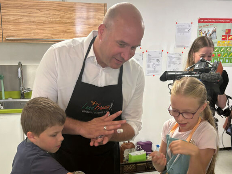 Ein Mann und zwei Kinder stehen an einem Tisch.